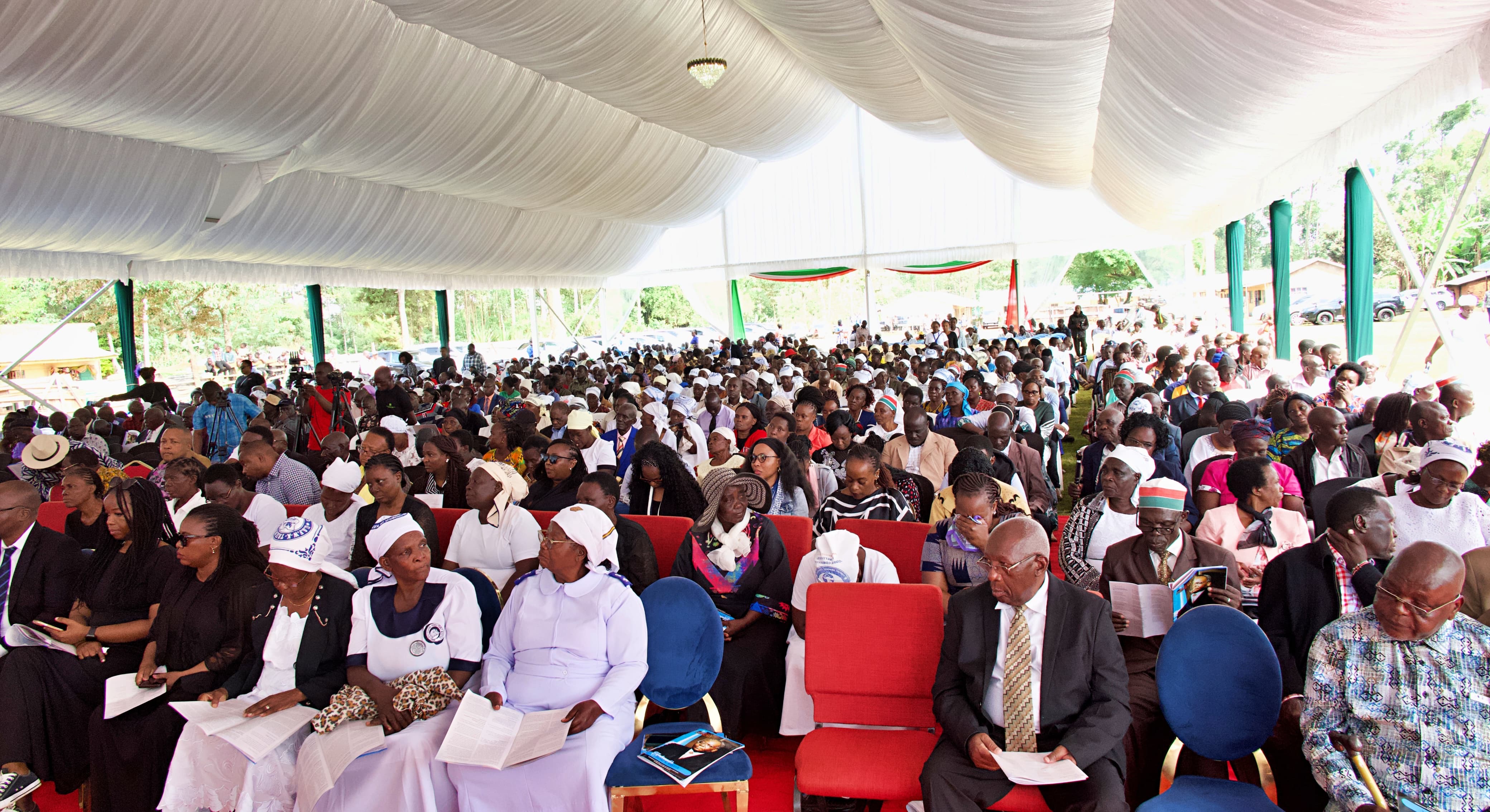 Mourners follow the proceedings with solemn expressions during the funeral service of Ambassador Boaz Mbaya in Vihiga County.