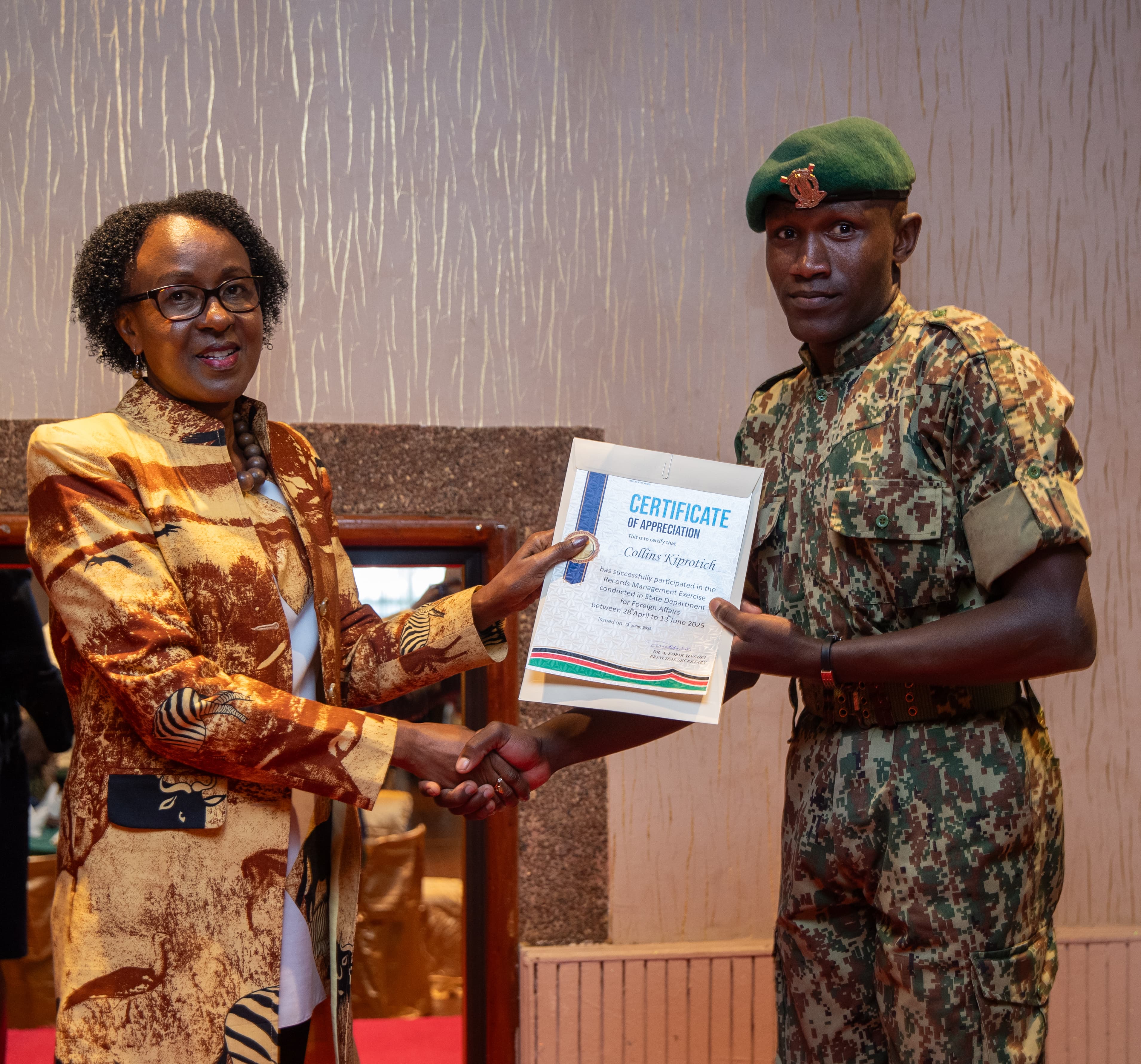 Ag. Director General, Political and Diplomatic Affairs, Amb. Lucy Kiruthu hands certificate to an NYS officer